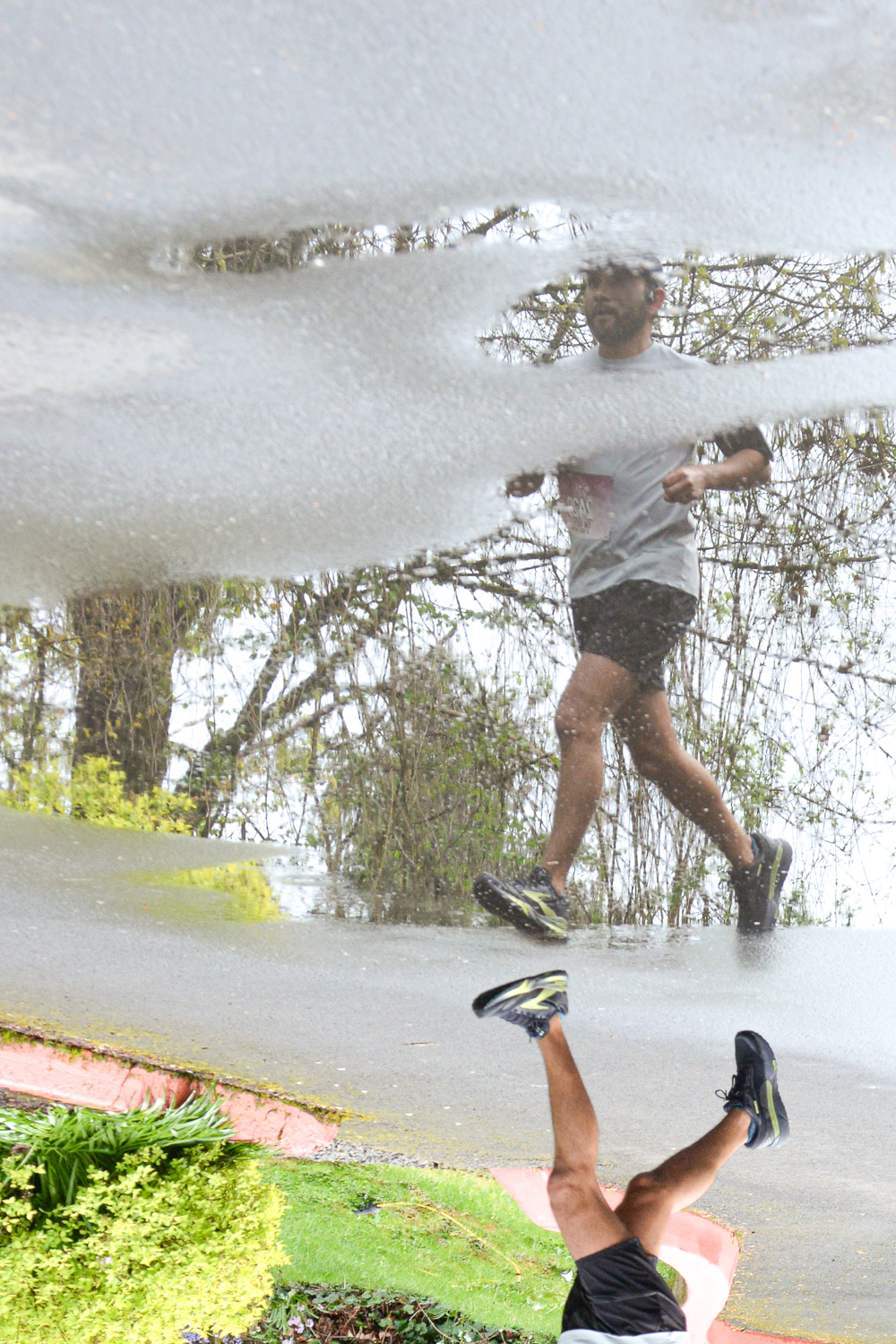 Man running reflected in a puddle.